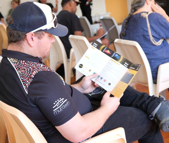 A person sitting and reading a brochure in a community yarning session.
